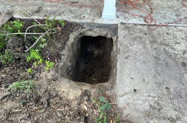 A house with an uneven foundation due to a hole next to it.