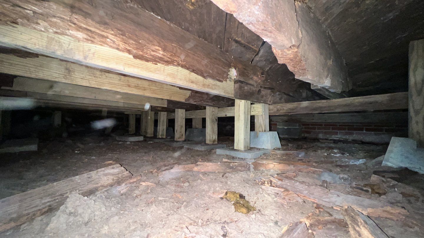 A basement with wooden beams and a wooden floor in need of foundation repair.