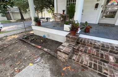 A front porch with brick steps and potted plants in need of foundation repair.