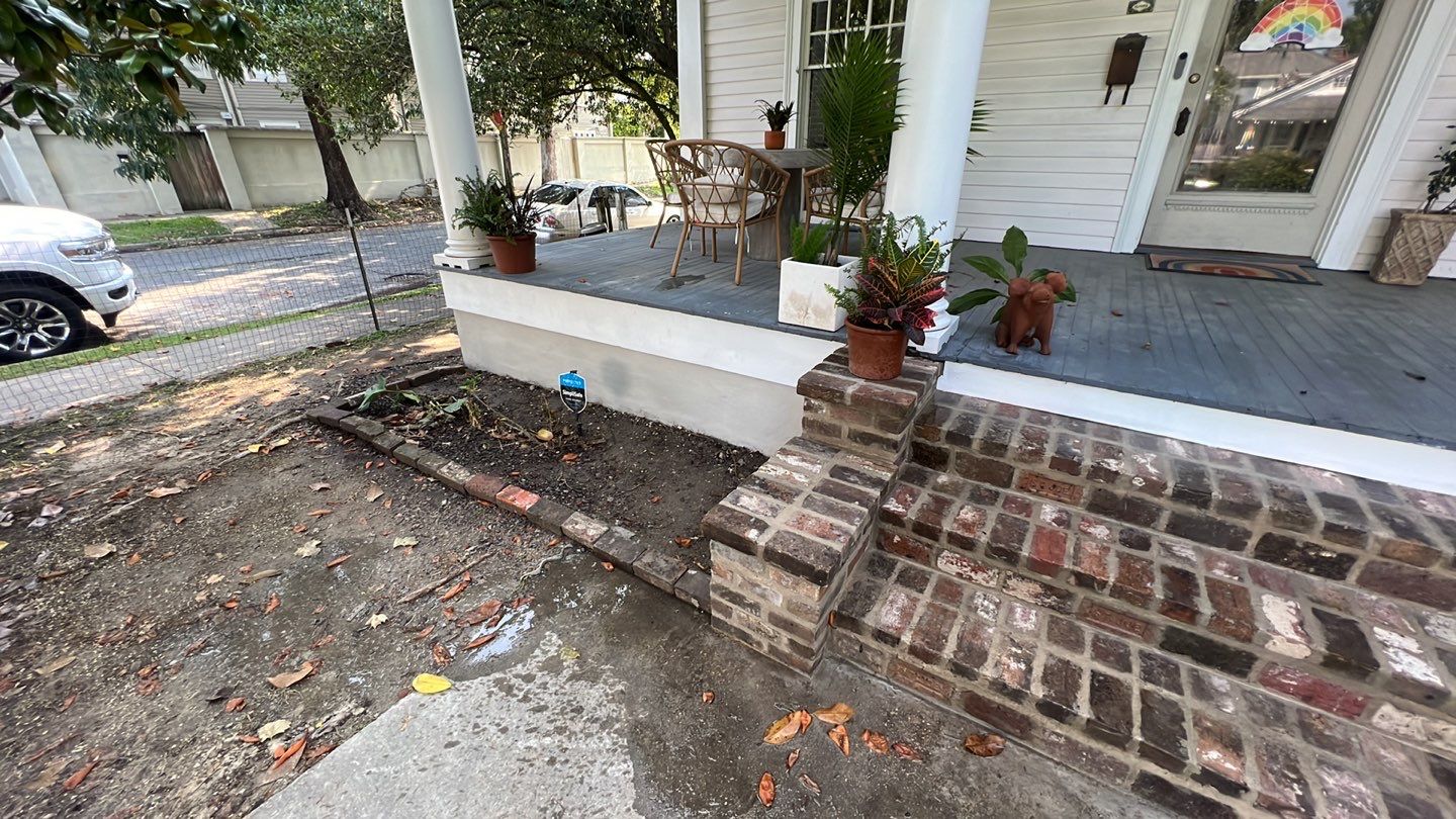A front porch with brick steps and potted plants in need of foundation repair.