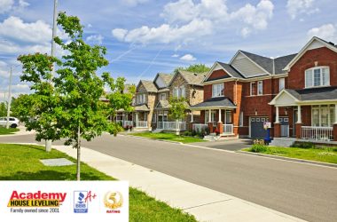 A row of houses with a sign that says academy of real estate offering Foundation Repair services.