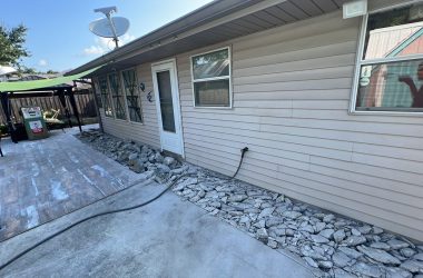 A small backyard with rocks and a lawn mower requiring house leveling.