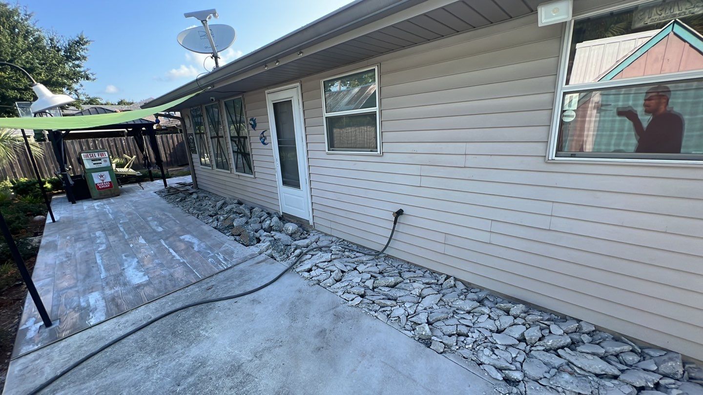 A small backyard with rocks and a lawn mower requiring house leveling.