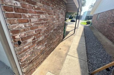 A brick wall next to a sidewalk with a door, indicating home elevation.