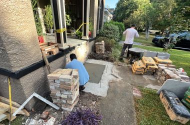 A group of men are working on house foundation repair in front of a brick wall.