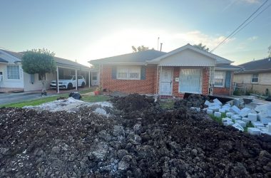 A house undergoing foundation repair with a pile of dirt in front of it.