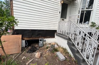 A house with a stairway and a metal railing undergoing foundation repair.