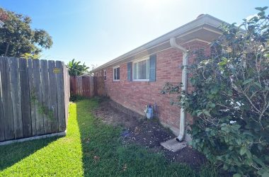 A backyard with a fence and bushes.