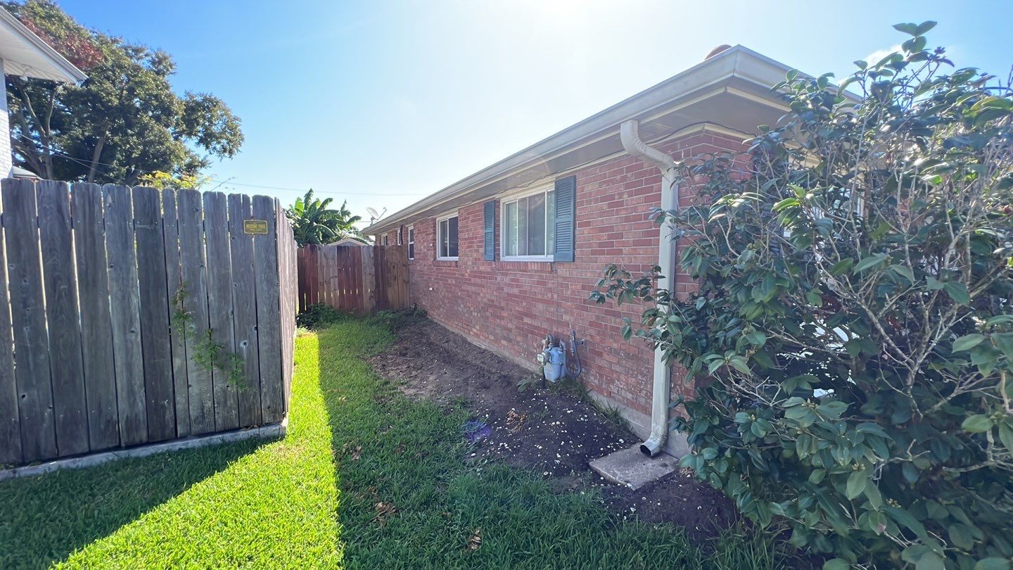 A backyard with a fence and bushes.