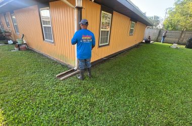 A man in a blue shirt standing in front of a house.