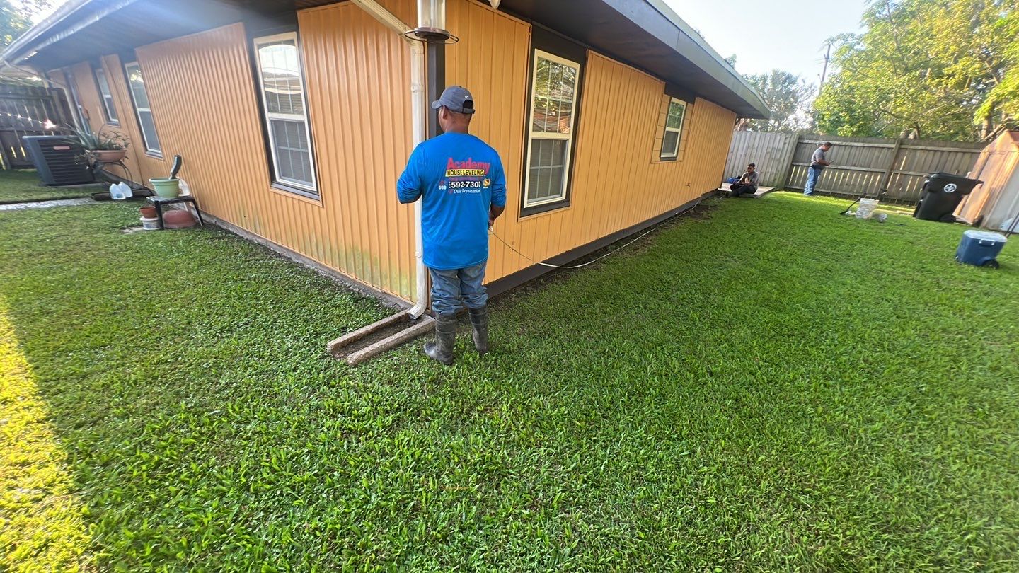 A man in a blue shirt standing in front of a house.