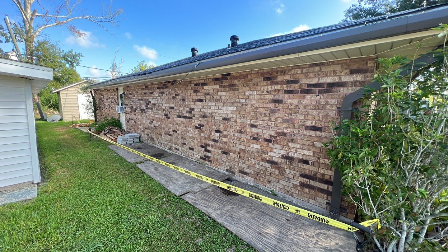 A brick house with a caution tape around it.