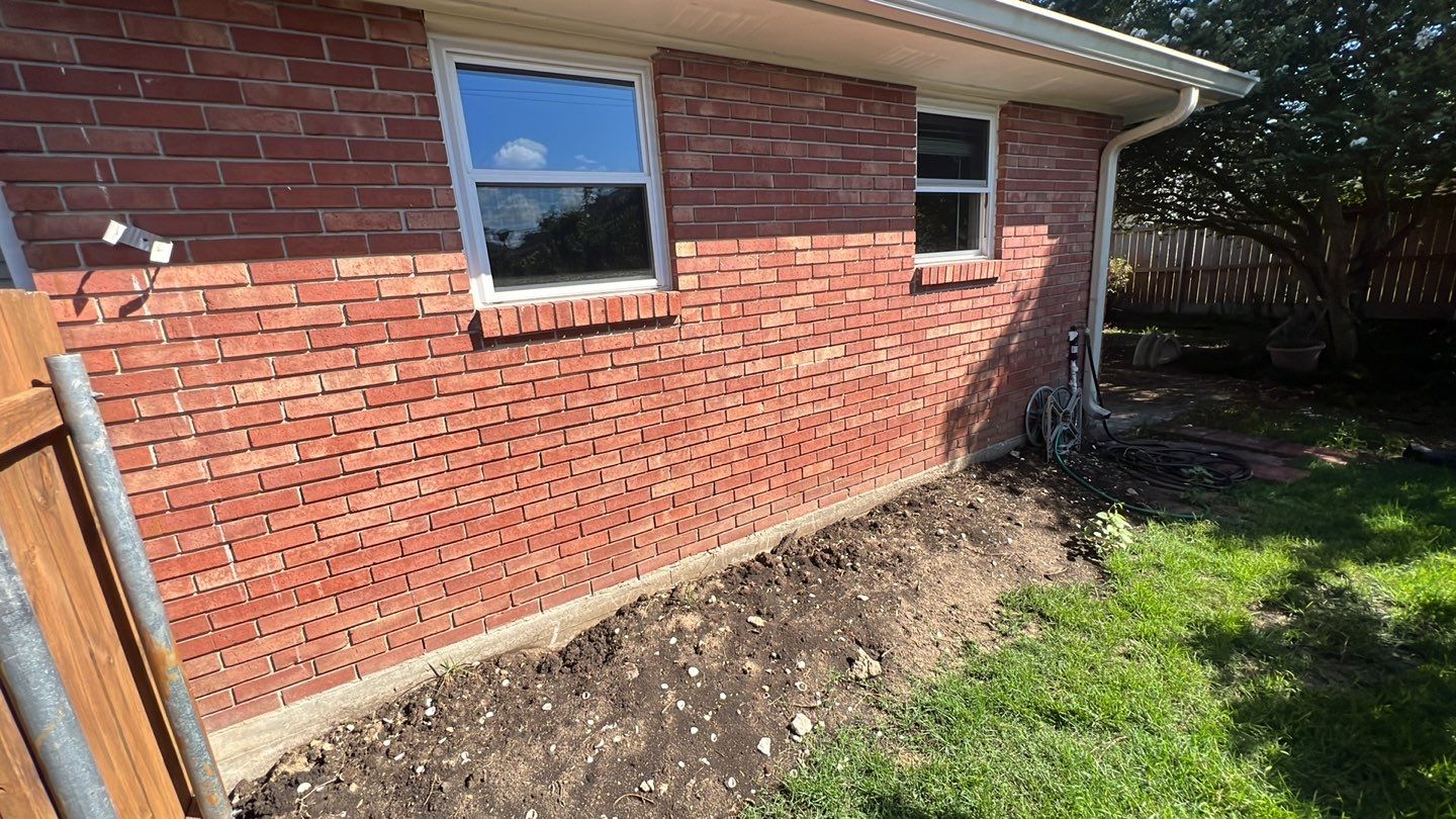 A backyard with a brick wall and a window.