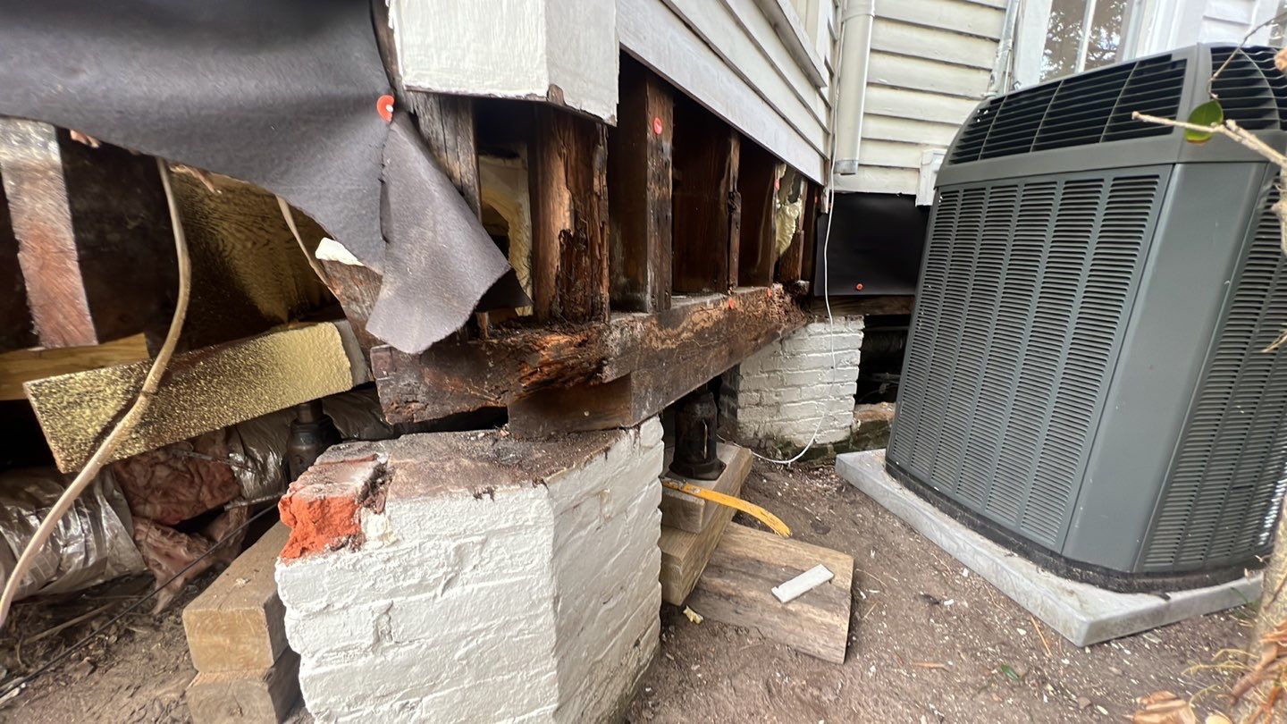 A damaged air conditioner in front of a house.