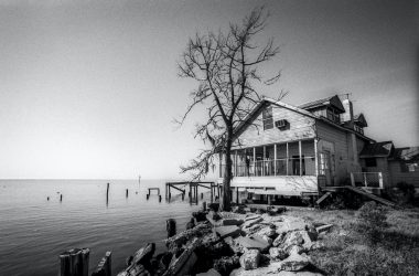 a black and white photo of a house by the water