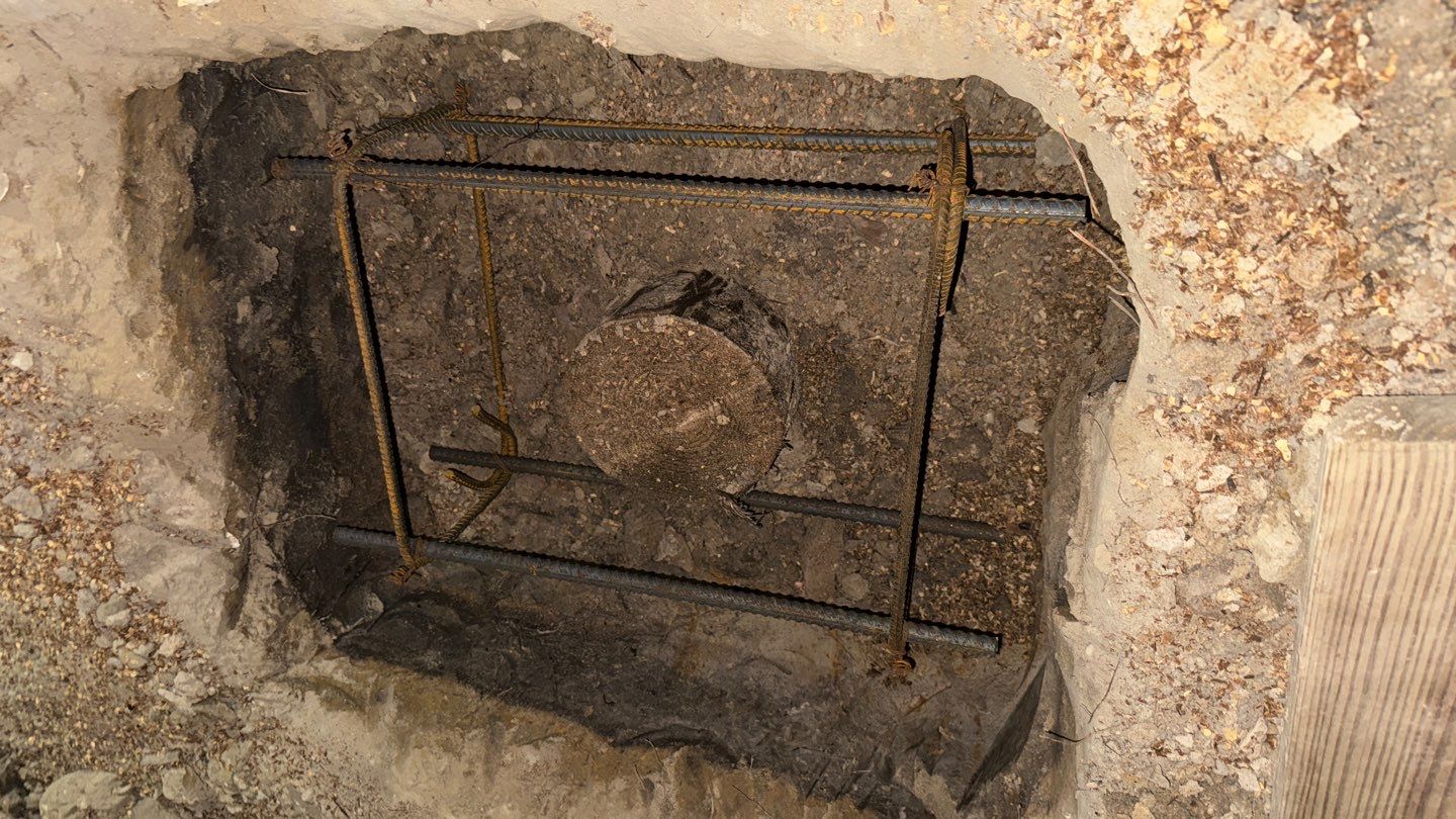 A hole in the ground with a metal rod in it.