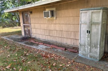 A wooden cabinet sits on the side of a house.