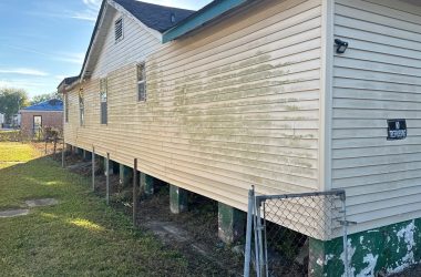 A house with white siding and a fence next to it.