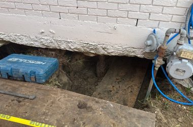 A hole in the ground next to a house.