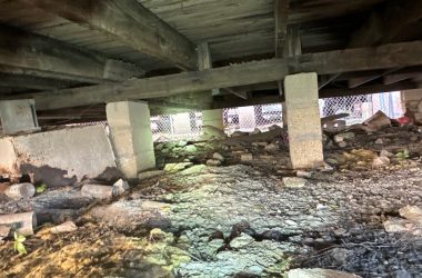 The underside of a building with a lot of dirt and rocks.