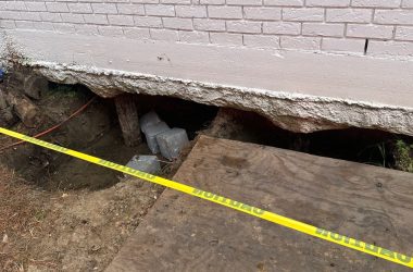 A hole in the ground next to a yellow tape.
