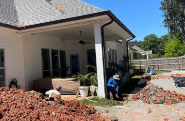 A group of men are working on a house with a brick patio.