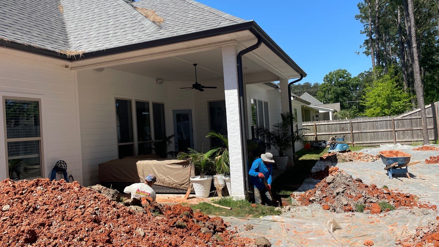 A group of men are working on a house with a brick patio.