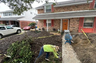 A man is digging a hole in front of a house.