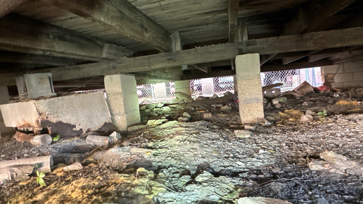 The underside of a building in Louisiana with a lot of dirt and rocks, potentially suffering from pier and beam foundation failures.