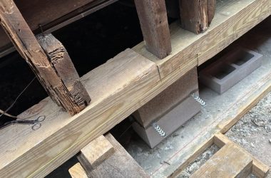 A piece of wood is being used to build a house with a pier and beam foundation.